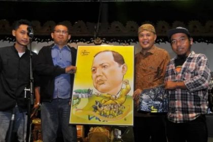 Mantan Bupati Karanganyar Juliyatmono menerima kado karikatur dari Relawan Kebakkramat Bersatoe saat wayangan di Alun-alun setempat pada Senin (29/7/2024) malam. (FOTO: Solopos.com/Indah Septiyaning Wardani)