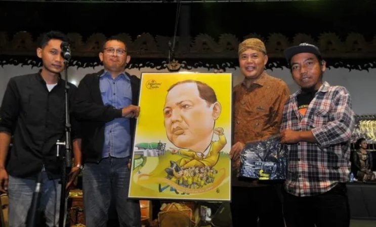 Mantan Bupati Karanganyar Juliyatmono menerima kado karikatur dari Relawan Kebakkramat Bersatoe saat wayangan di Alun-alun setempat pada Senin (29/7/2024) malam. (FOTO: Solopos.com/Indah Septiyaning Wardani)